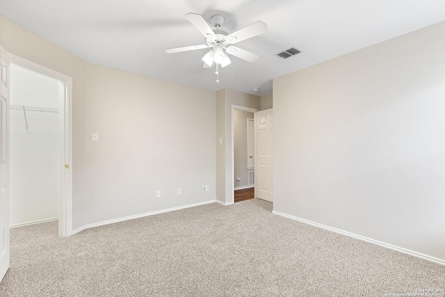 carpeted empty room with baseboards, visible vents, and ceiling fan