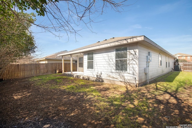 rear view of property featuring a lawn and a fenced backyard