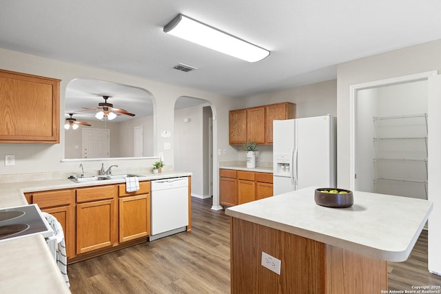 kitchen with white appliances, visible vents, arched walkways, light countertops, and a sink