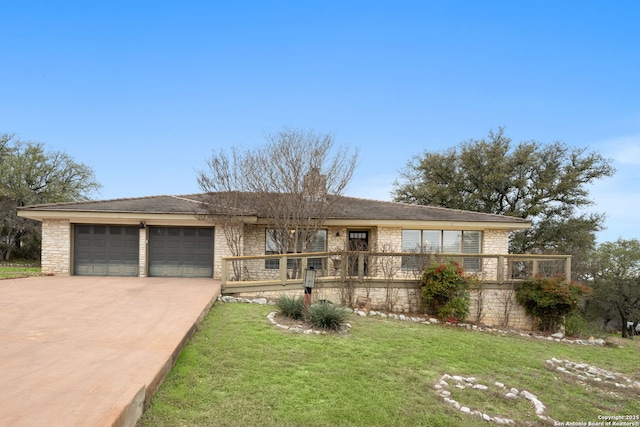 view of front of property featuring a front lawn, stone siding, driveway, and an attached garage