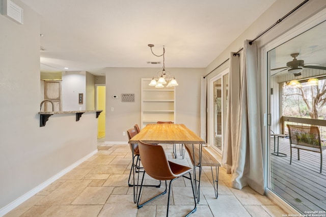 dining area featuring baseboards, visible vents, stone tile floors, and ceiling fan with notable chandelier