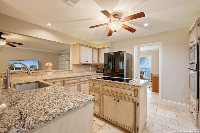 kitchen with tasteful backsplash, visible vents, light brown cabinets, a sink, and black appliances