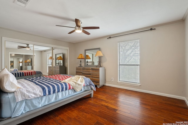 bedroom with crown molding, a closet, visible vents, wood finished floors, and baseboards