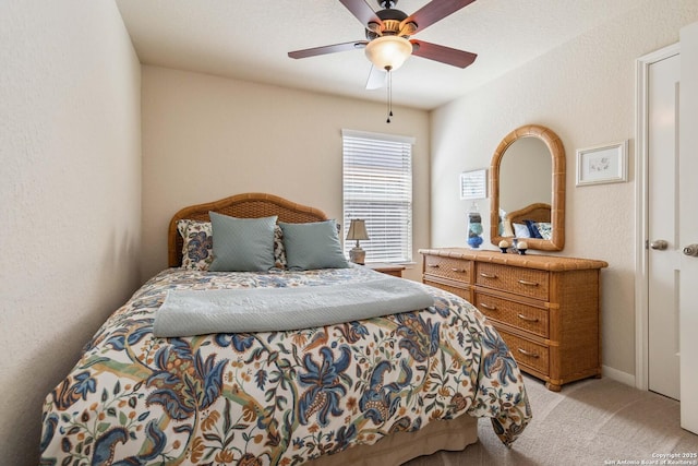 bedroom with light carpet, ceiling fan, and a textured wall