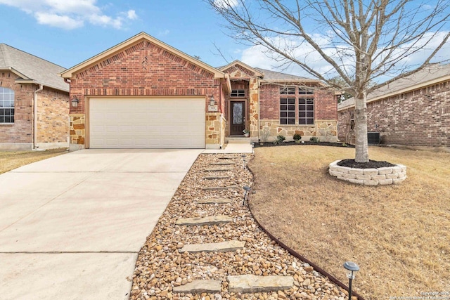 single story home featuring a garage, central AC unit, concrete driveway, stone siding, and brick siding