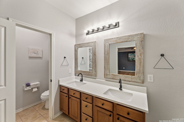 full bath with toilet, double vanity, a sink, and tile patterned floors