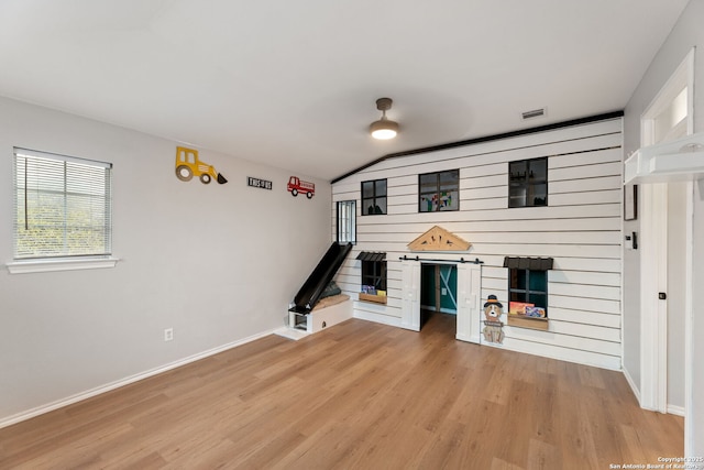 unfurnished living room featuring light wood-type flooring, visible vents, baseboards, and vaulted ceiling