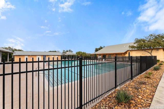 community pool with a patio area and fence