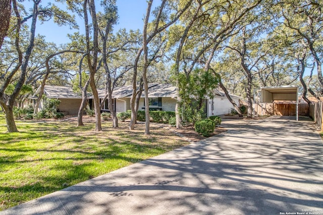 view of front facade with concrete driveway, a front yard, and fence