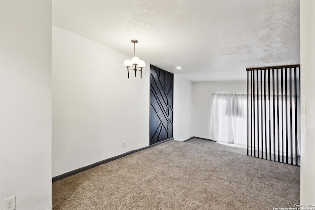 carpeted empty room with a barn door, baseboards, and a textured ceiling