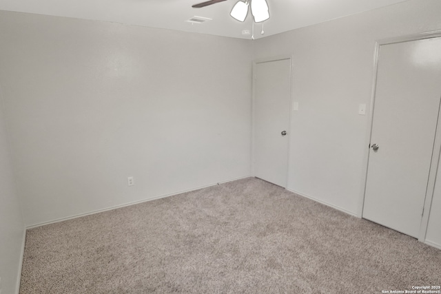 empty room featuring ceiling fan, visible vents, and carpet flooring