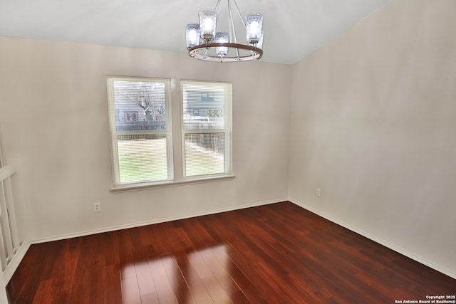 unfurnished dining area featuring baseboards, a chandelier, and wood finished floors