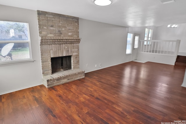 unfurnished living room featuring wood-type flooring, a fireplace, and baseboards