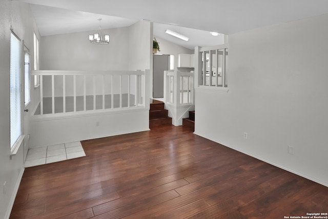 unfurnished room featuring an inviting chandelier, stairway, vaulted ceiling, and wood finished floors