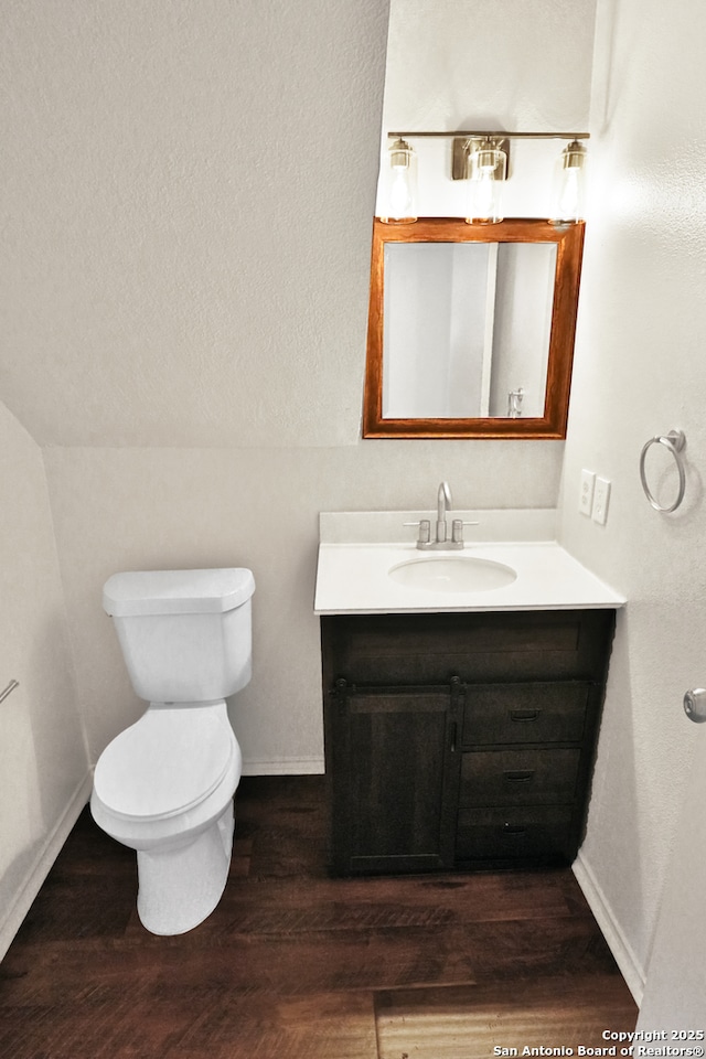 bathroom featuring baseboards, vanity, toilet, and wood finished floors