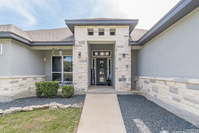 property entrance with stone siding, a shingled roof, and stucco siding