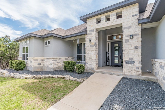 doorway to property with stone siding, roof with shingles, and stucco siding