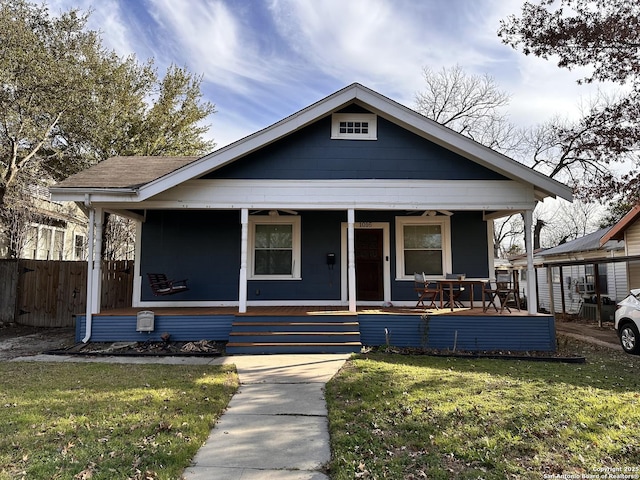 bungalow featuring a porch, a front lawn, and fence