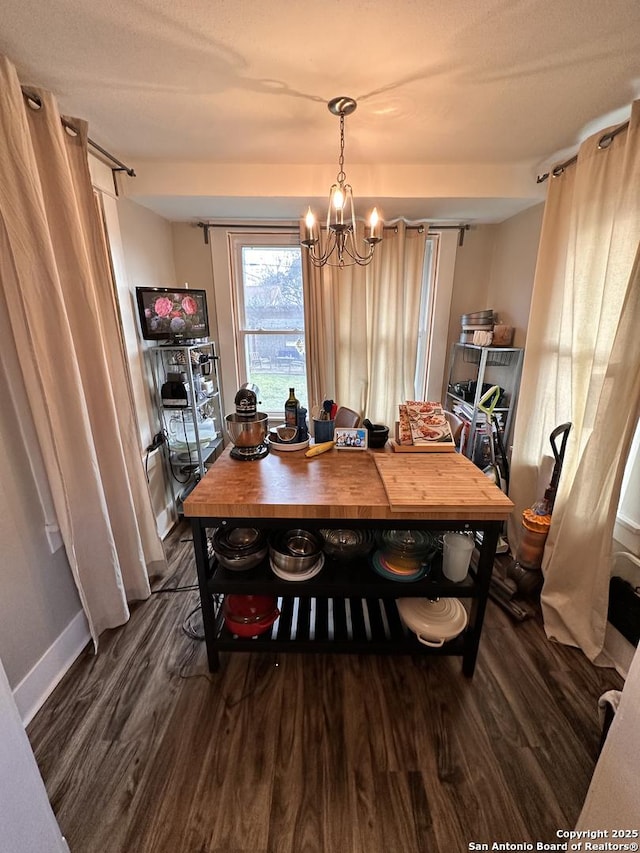 dining space featuring dark wood-style floors, baseboards, and a notable chandelier