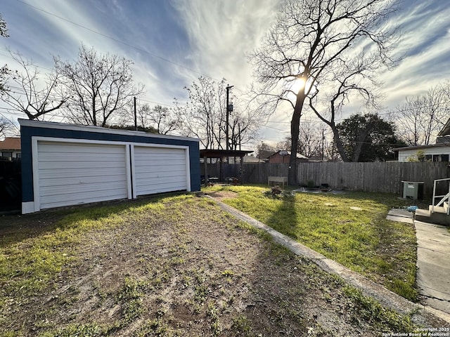 view of yard featuring a garage, fence, and an outdoor structure