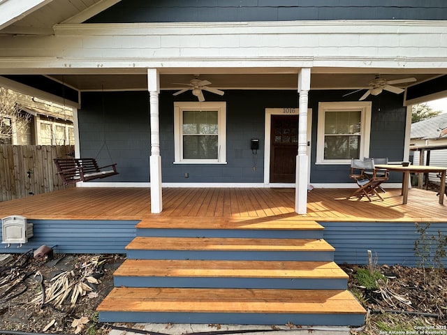 doorway to property with ceiling fan, fence, and a porch