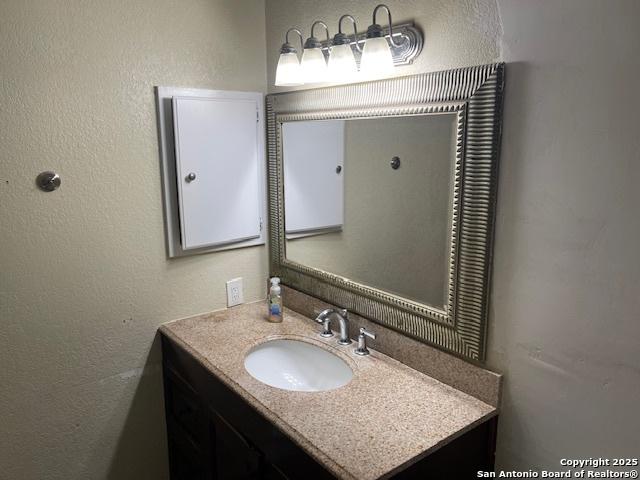 bathroom featuring a textured wall and vanity