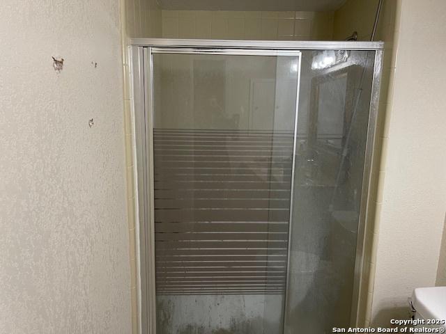 bathroom featuring a stall shower and a textured wall