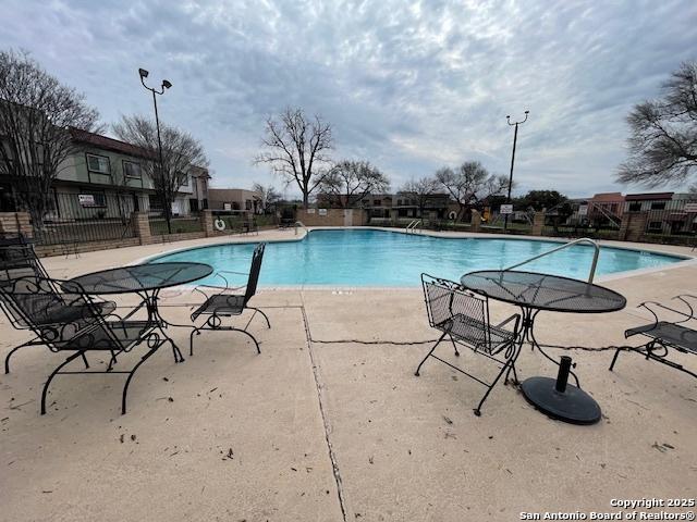 pool with a patio area and fence