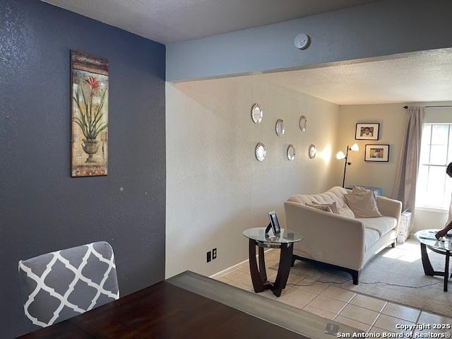 living room featuring light tile patterned floors, a textured ceiling, and a textured wall