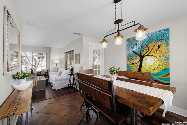 dining space featuring dark tile patterned flooring, visible vents, and baseboards