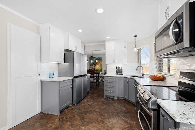 kitchen with backsplash, gray cabinets, stainless steel appliances, and a sink