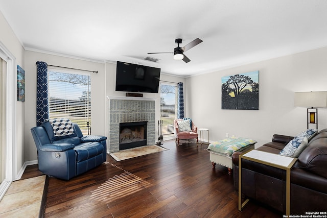 living area with a fireplace, crown molding, visible vents, a ceiling fan, and wood finished floors