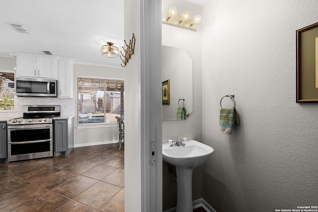 bathroom with visible vents, decorative backsplash, a sink, and a textured wall