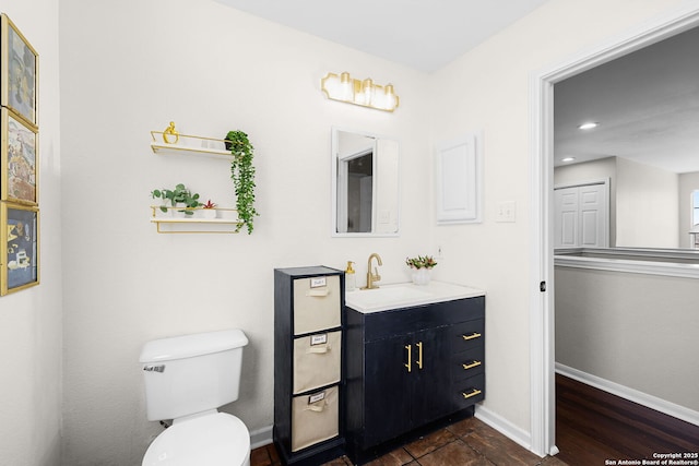 bathroom with toilet, vanity, and baseboards