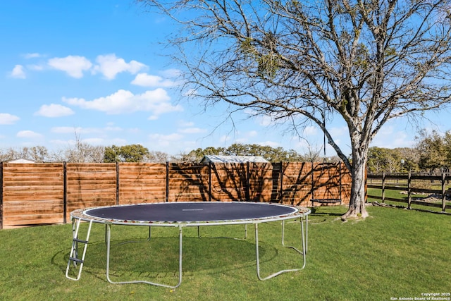 view of yard with a trampoline and a fenced backyard