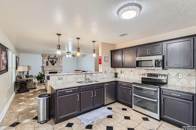 kitchen featuring a peninsula, appliances with stainless steel finishes, a sink, and tasteful backsplash