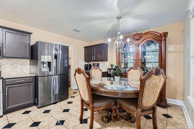 dining space with light tile patterned floors, baseboards, a chandelier, and a textured ceiling