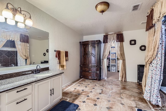 full bath with visible vents, a textured wall, a textured ceiling, and vanity