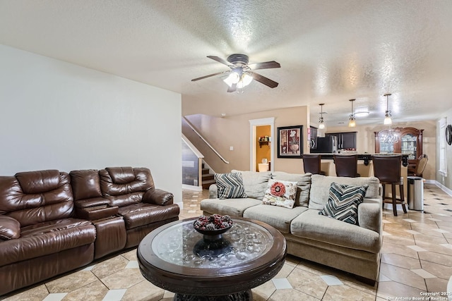 living area with a ceiling fan, light tile patterned floors, stairway, and a textured ceiling