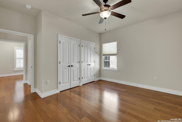948 Hudson, New Braunfels, TX 78130 - unfurnished bedroom with baseboards, wood-type flooring, a ceiling fan, and multiple closets