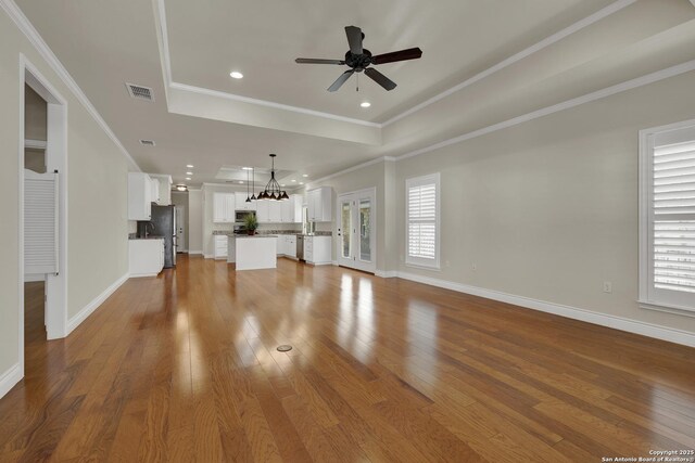 948 Hudson, New Braunfels, TX 78130 - unfurnished living room featuring visible vents, a raised ceiling, hardwood / wood-style floors, and ornamental molding
