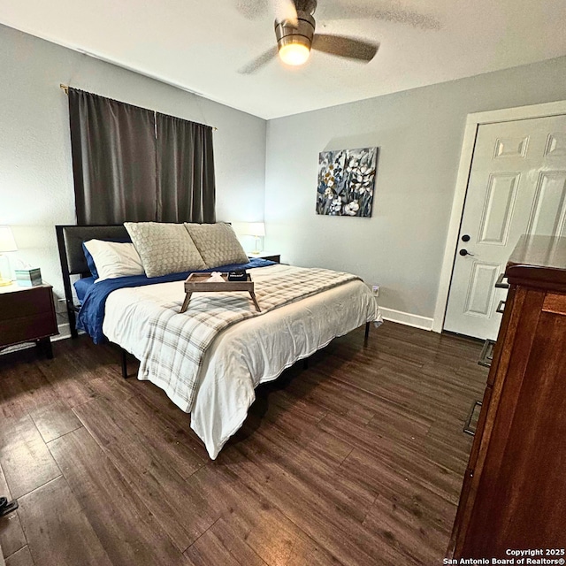 bedroom with ceiling fan, baseboards, and dark wood-type flooring