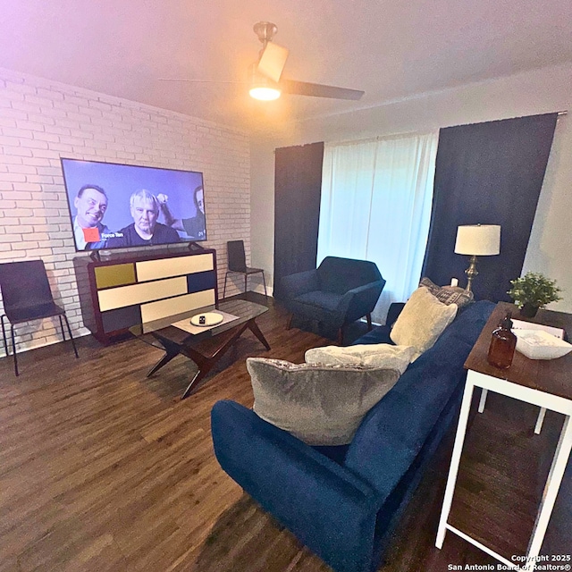 living area featuring brick wall, ceiling fan, and wood finished floors