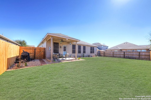 back of property with a patio, a yard, a fenced backyard, and a ceiling fan