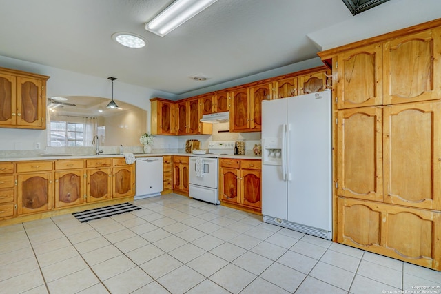 kitchen featuring white appliances, brown cabinets, light countertops, under cabinet range hood, and a sink