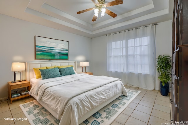 bedroom with ceiling fan, a raised ceiling, and light tile patterned flooring