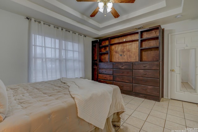 bedroom featuring ceiling fan, a tray ceiling, light tile patterned flooring, and visible vents