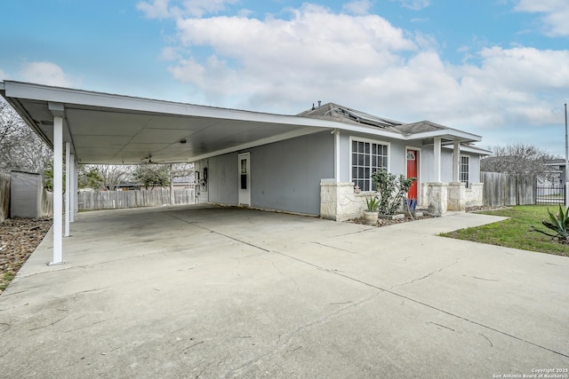 view of front of property featuring an attached carport, roof mounted solar panels, driveway, and fence