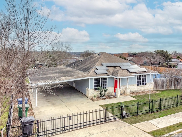 view of front of property with stone siding, a fenced front yard, a front lawn, a carport, and stucco siding