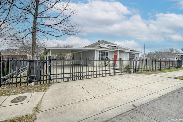 view of front of property featuring a fenced front yard, roof mounted solar panels, an attached carport, and concrete driveway